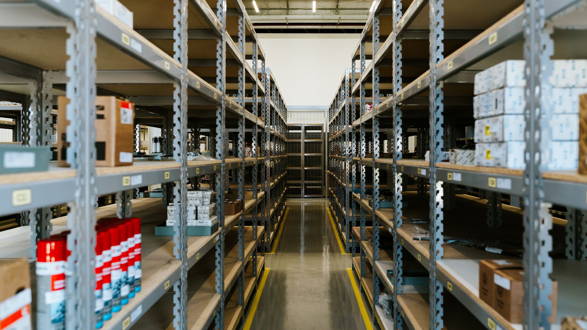 Wide view of an organized warehouse aisle lined with metal shelving and stored merchandise
