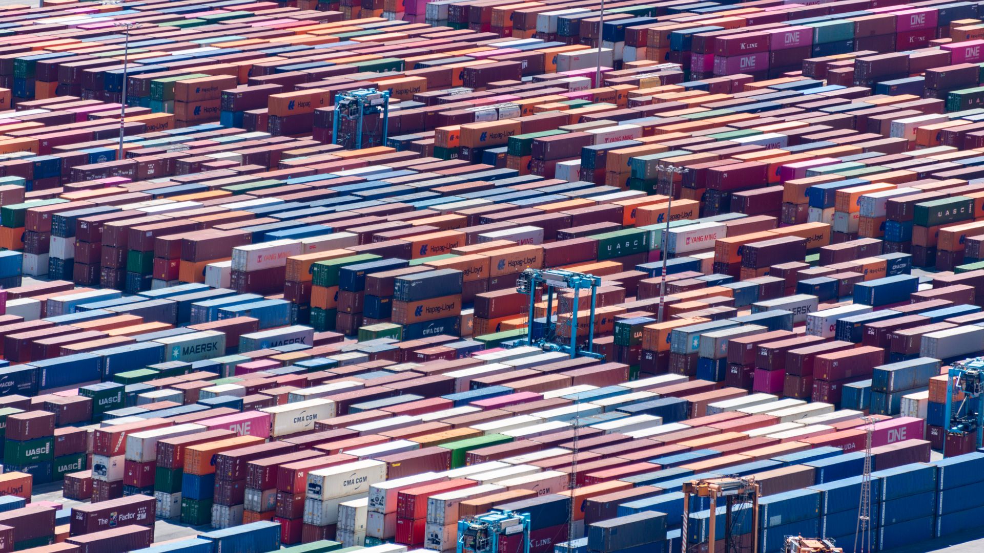 Aerial view of a container port with stacked shipping containers and cranes