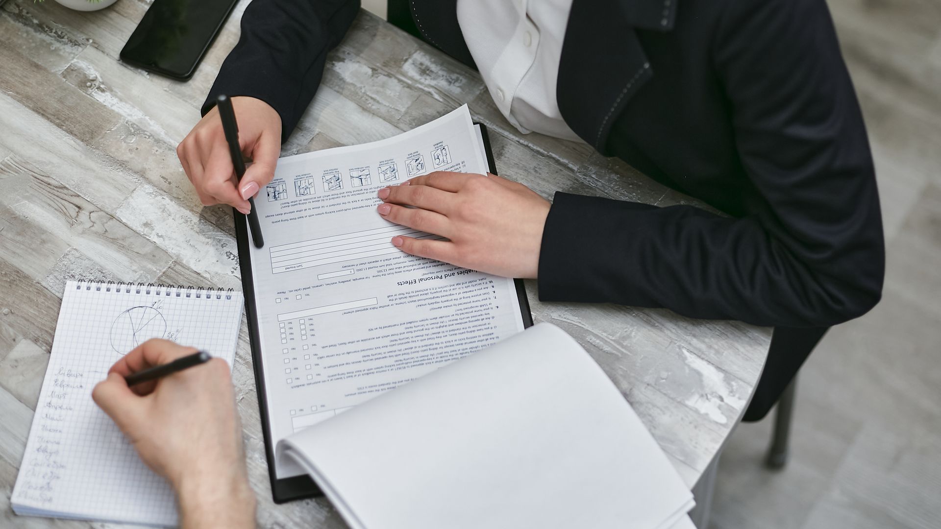 Two people at a desk reviewing proposal documents