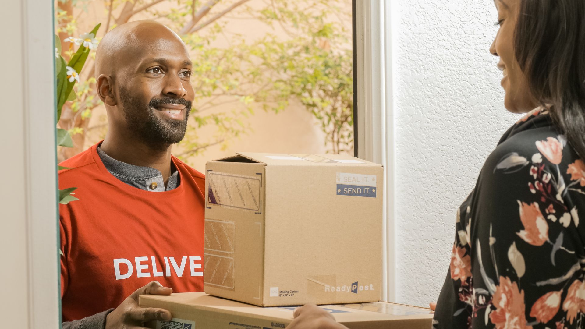 Delivery driver handing packages to a customer at her front door
