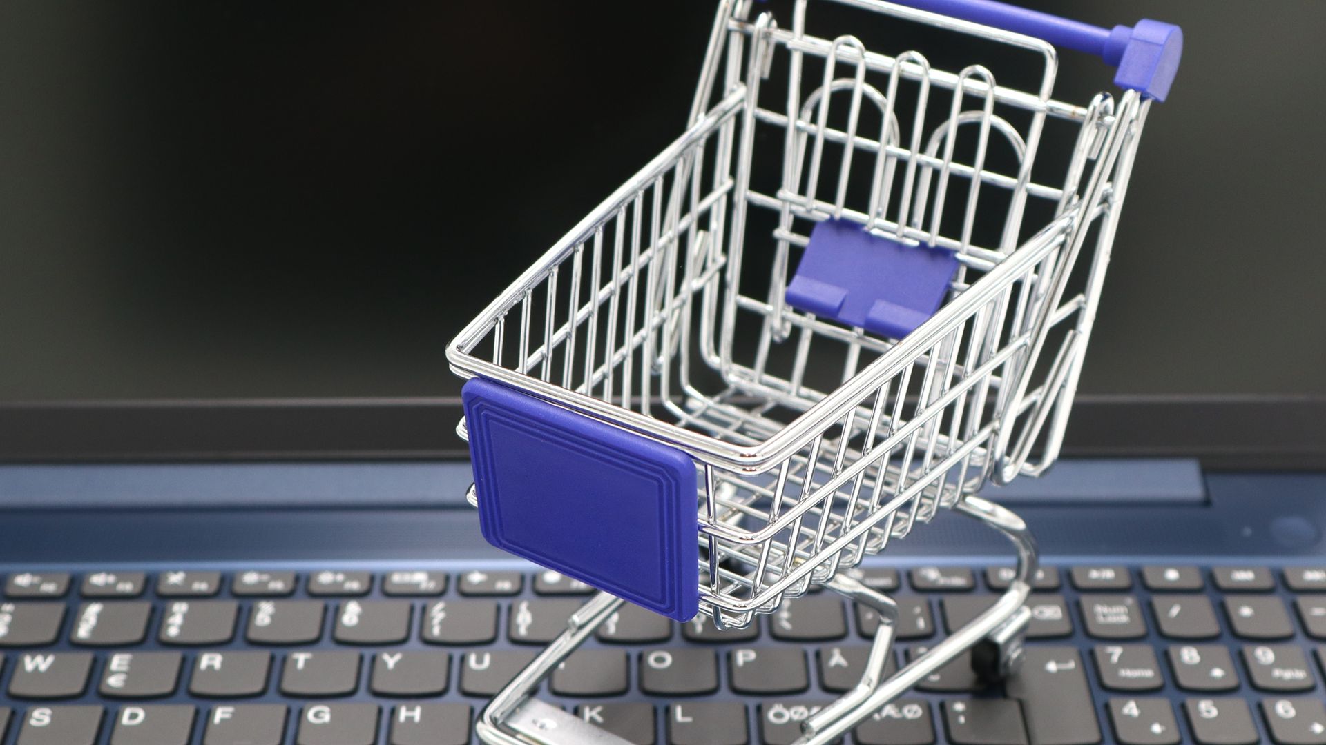 Miniature shopping cart sitting on a laptop keyboard