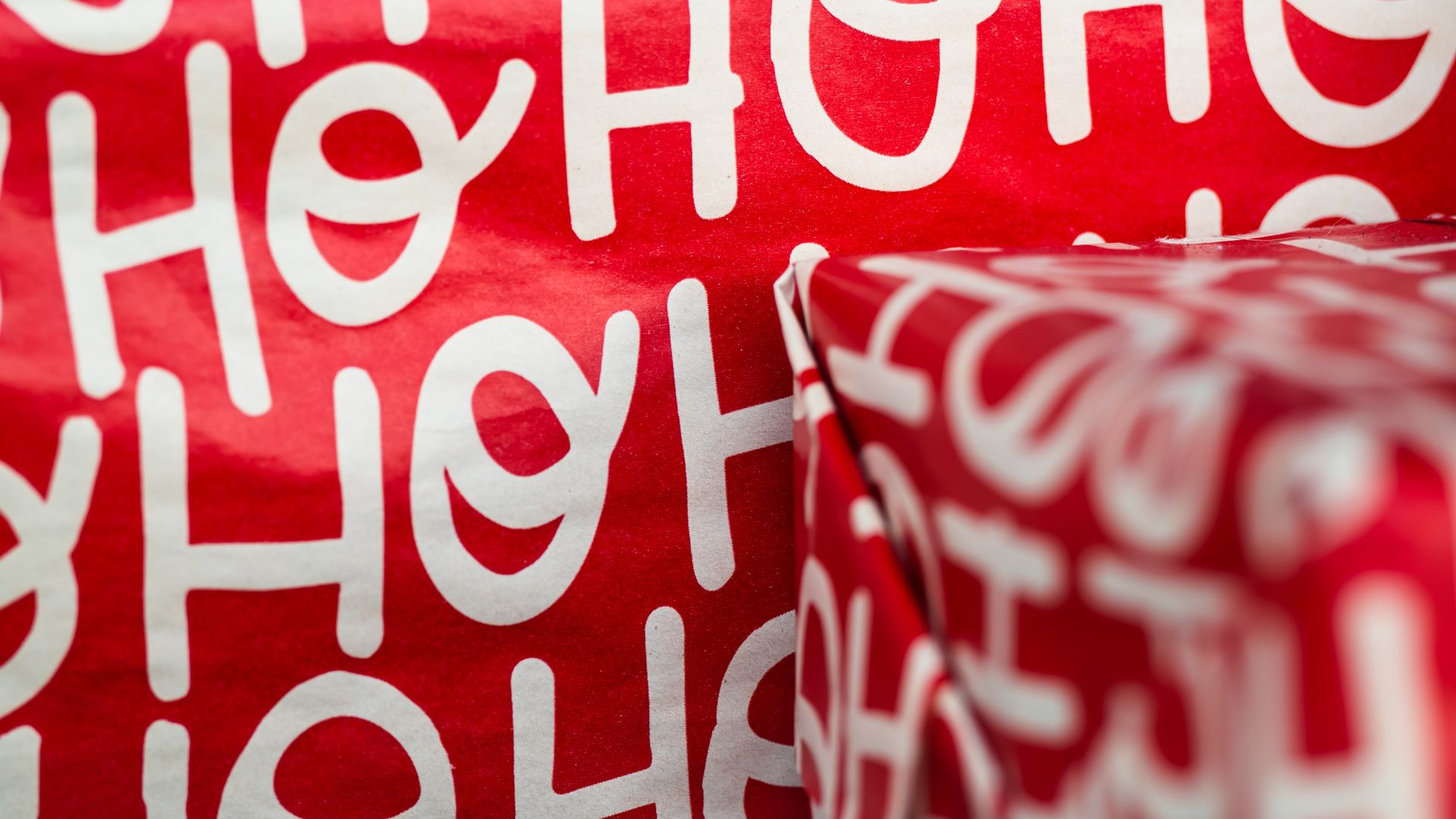 Gifts wrapped in red holiday paper with white lettering