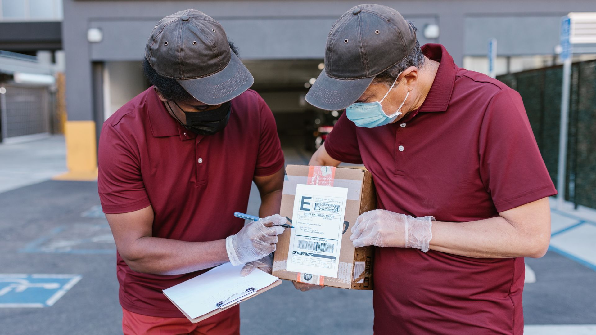 Two delivery workers checking the shipping label on a cardboard package