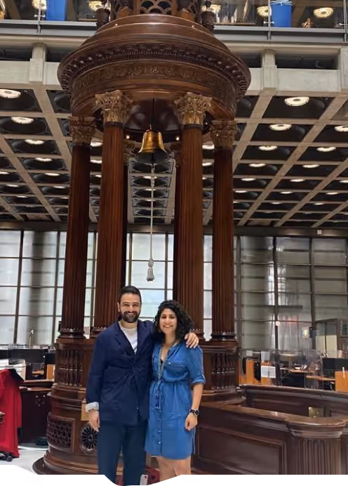a happy couple standing inside a building that has a bell in the center
