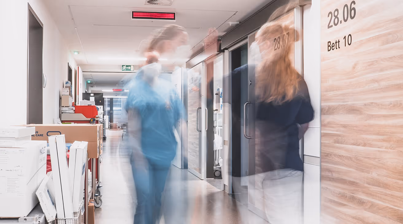 Zwei Pflegerinnen geben sich ein High Five im Vorbeigehen auf der Intensivstation