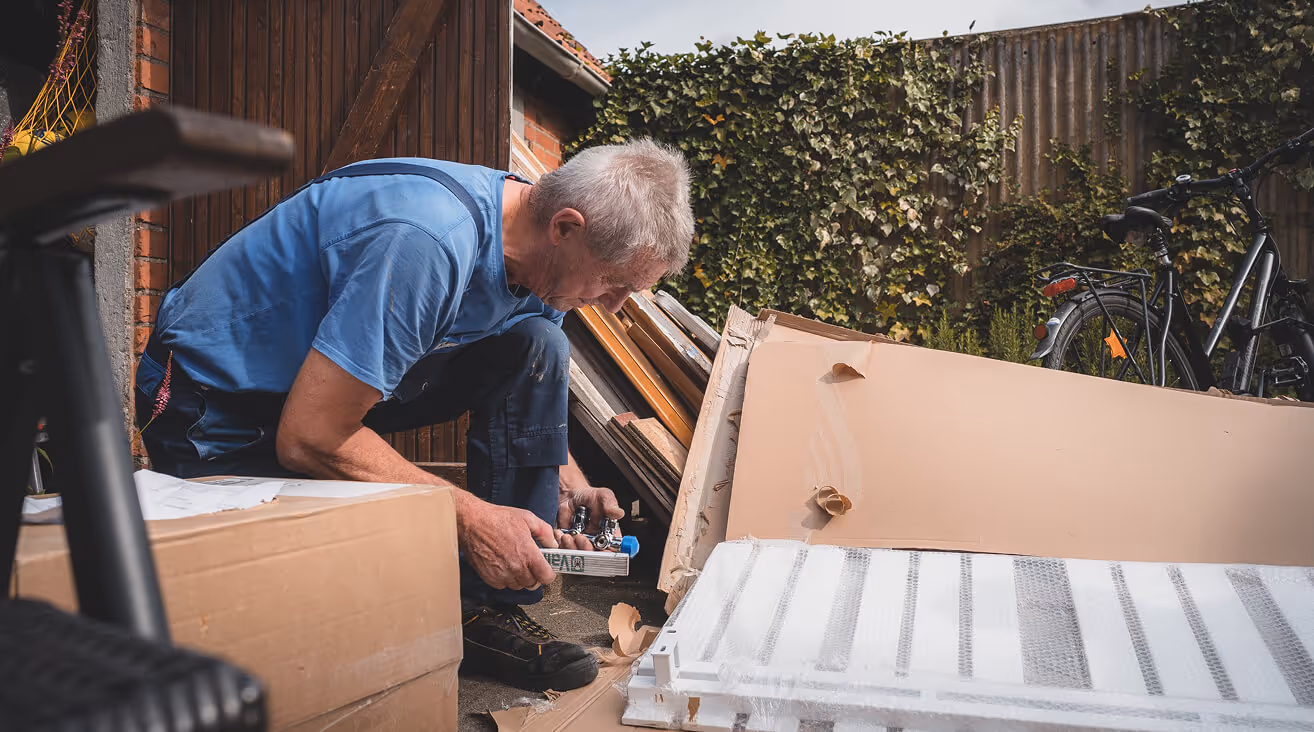 Ein Handwerker packt eine Heizung aus einem Karton aus