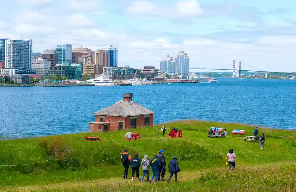 Guests explore Georges Island National Historic Site. The Halifax Skyline can been seen in the distance.