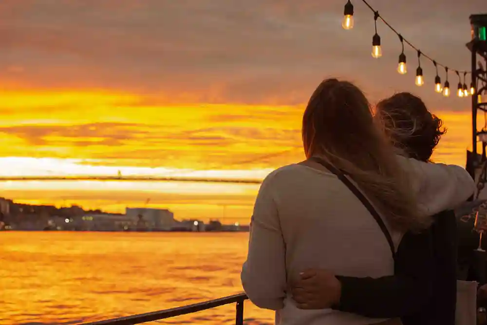 A mom and daughter look towards a beautiful sunset while on the Sunset Cruise aboard the Tall Ship Silva.