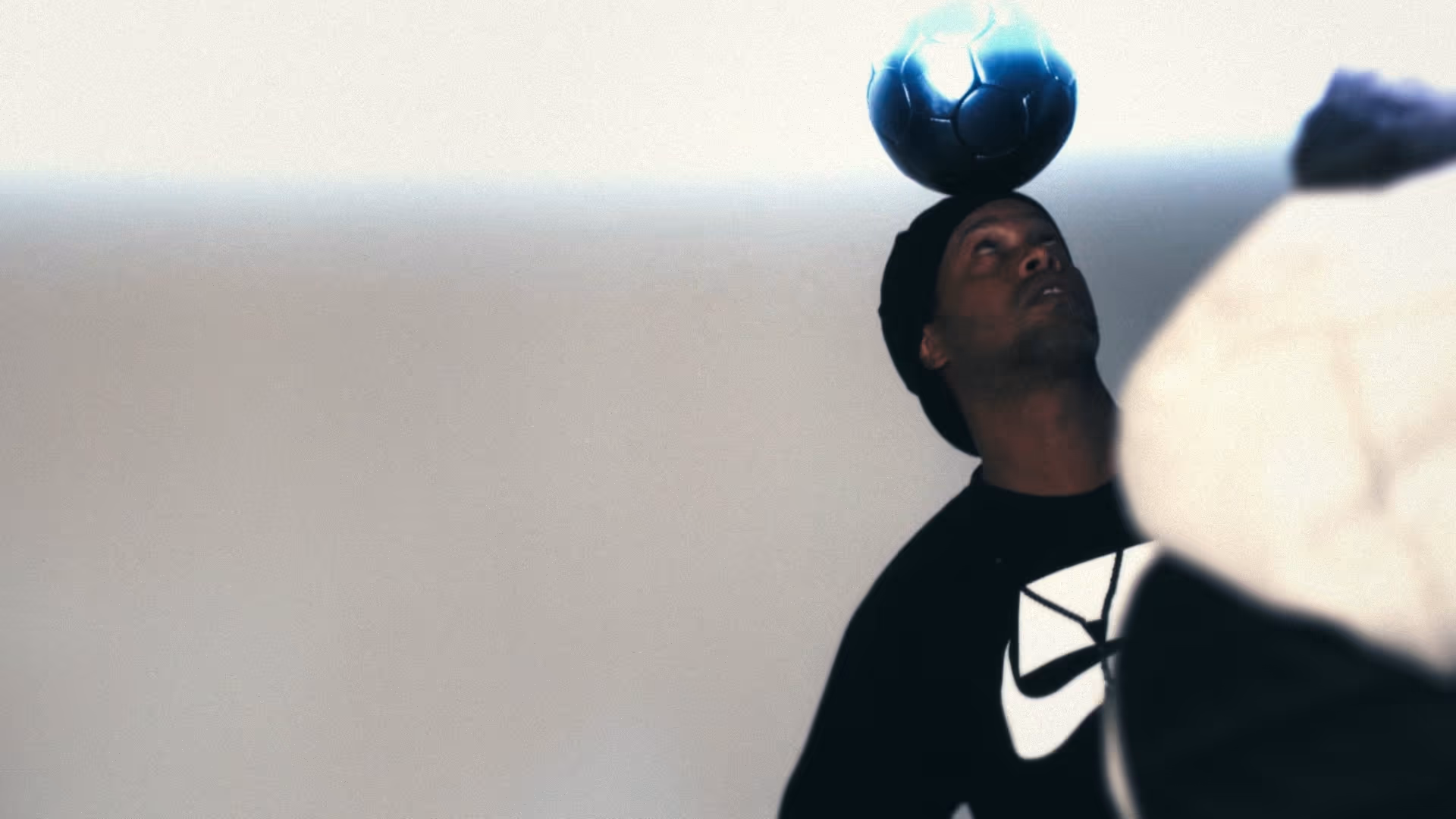 Ronaldinho juggles a football on his head.