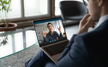 Person participating in a video call on a laptop, showing a woman on the screen gesturing with her hands.