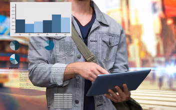 Person holding a tablet with overlaid digital charts and graphs against a blurred urban background.