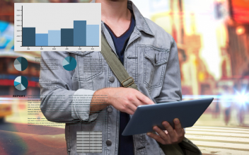 Person holding a tablet with overlaid digital charts and graphs against a blurred urban background.