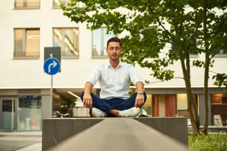 Homem branco de camisa social meditando em espaço urbano