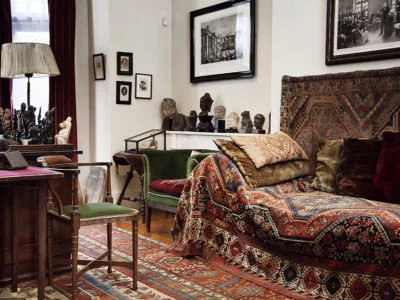 Divã original de Sigmund Freud em seu consultório em Viena, coberto por tapetes orientais e almofadas, símbolo do setting psicanalítico.