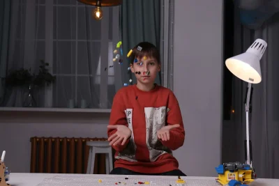 Garoto brincando e jogando peças coloridas para o alto, representando aprendizado e criatividade.