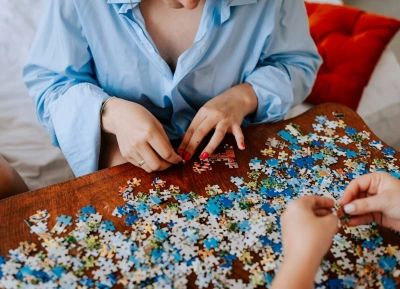 mulher montando quebra-cabeças sobre mesa junto com outra pessoa