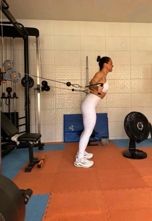 Mulher realizando exercício de musculação com elástico em ambiente doméstico