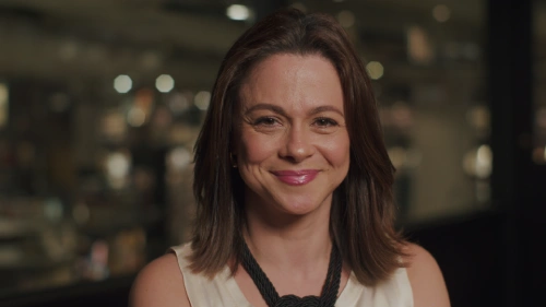 Retrato de mulher sorrindo em ambiente interno com fundo desfocado