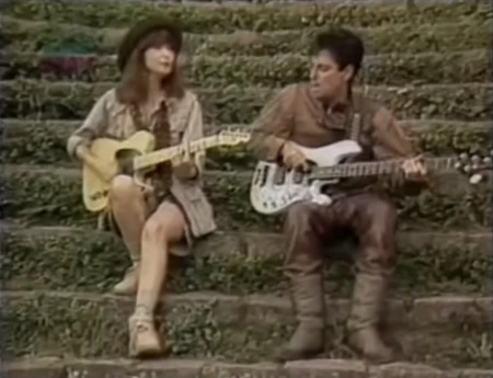 Rita Lee e Roberto de Carvalho tocando violão e baixo em cena do clipe Bwana