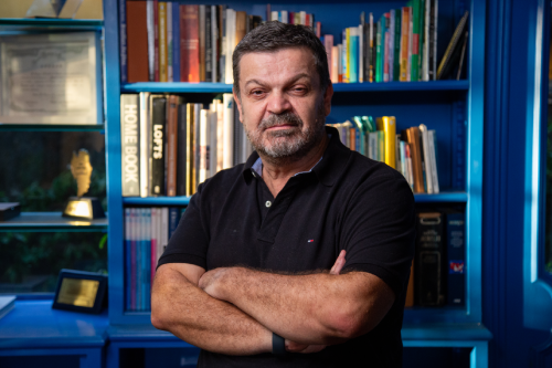 Retrato de Pedro de Santi com braços cruzados em frente a estante de livros