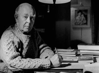 Retrato em preto e branco de John Bowlby escrevendo à mesa