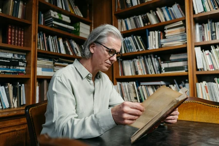 Homem mais velho lendo um livro em uma biblioteca