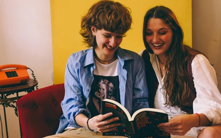 Duas jovens lendo juntas em um sofá