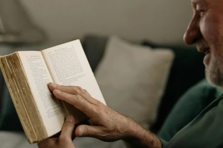 Pessoa lendo um livro aberto no sofá.