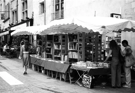 Banca de livros em uma rua com pessoas circulando ao redor.