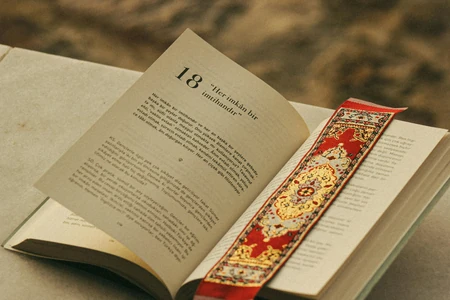 Livro aberto com marcador decorativo entre as páginas.
