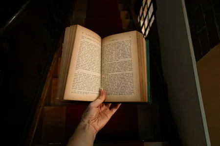 Livro aberto sendo segurado por uma mão