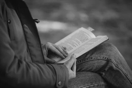 Pessoa sentada lendo um livro em preto e branco