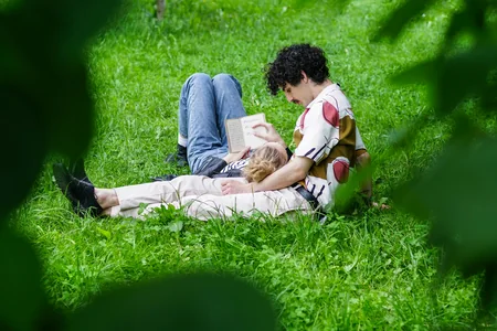 Casal deitado na grama lendo um livro