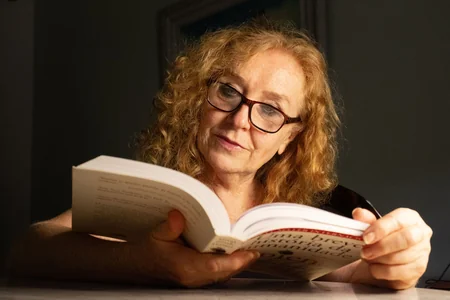 Mulher idosa de óculos lendo um livro