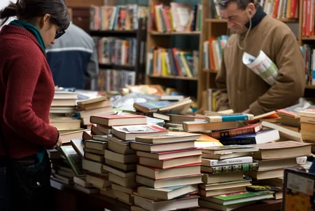 Pessoas observando livros expostos sobre uma mesa em livraria
