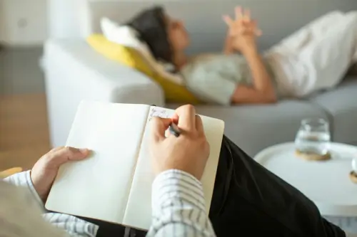 Psicólogo fazendo anotações enquanto atende uma paciente