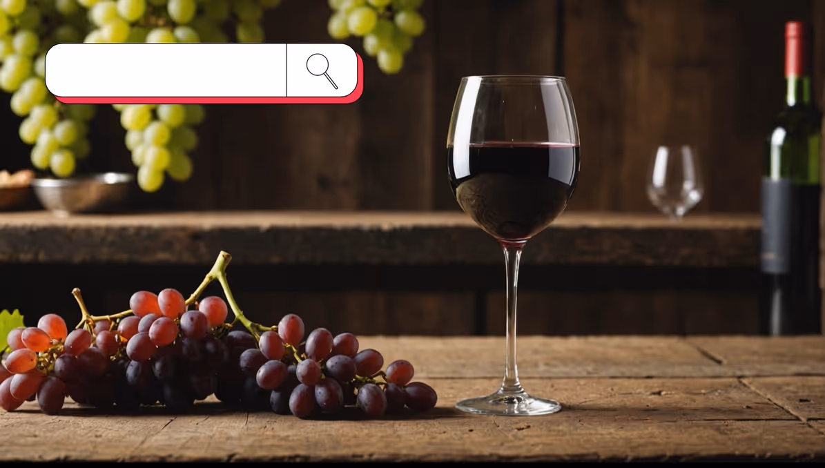 Glass of red wine on a rustic wooden table next to bunches of red grapes, with green grapes hanging in the background and a wine bottle in the distance; an empty search box with a magnifying glass icon is overlaid at the top left.