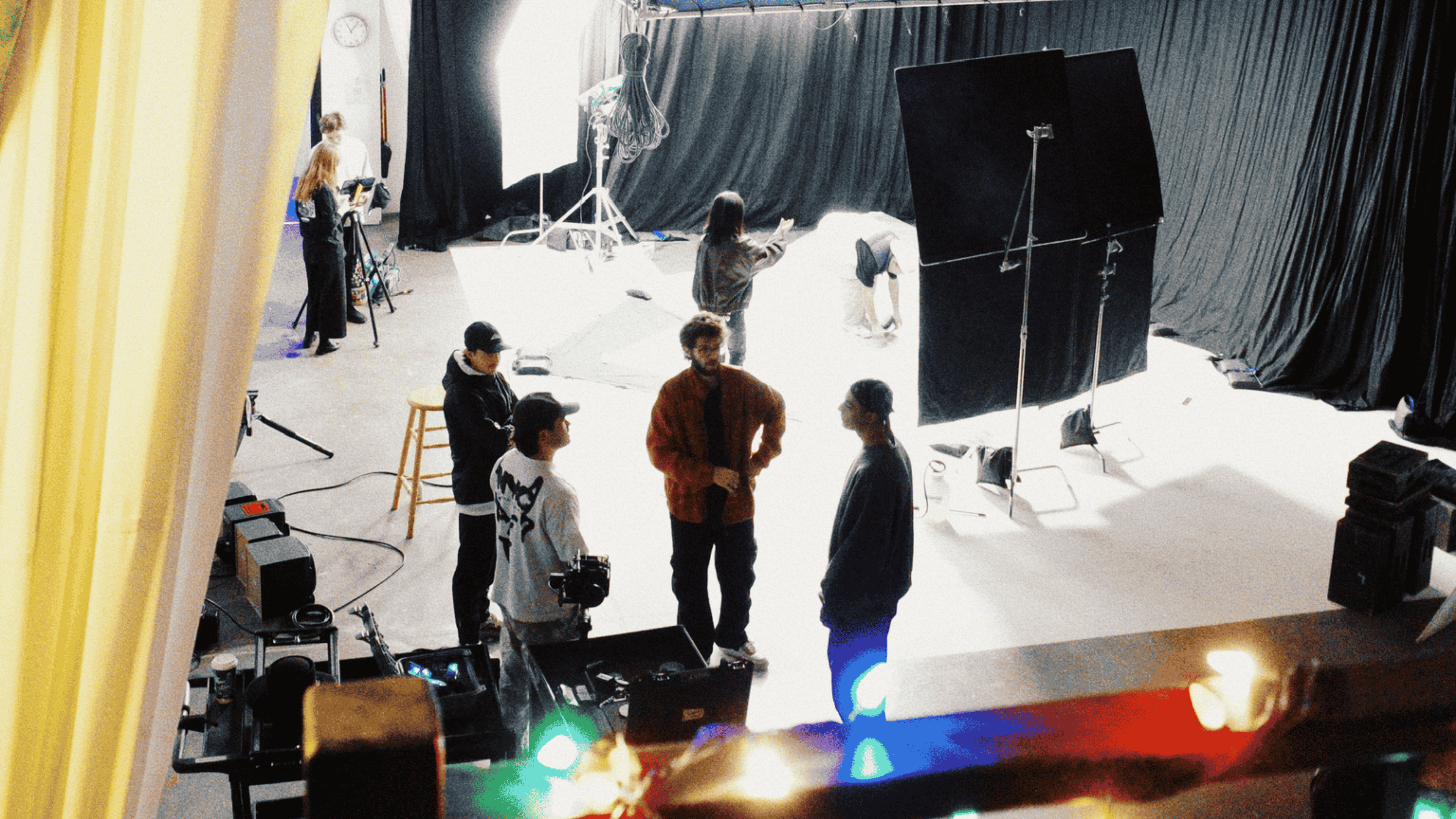 Group of people working on a photo shoot set with lighting equipment and backdrop.