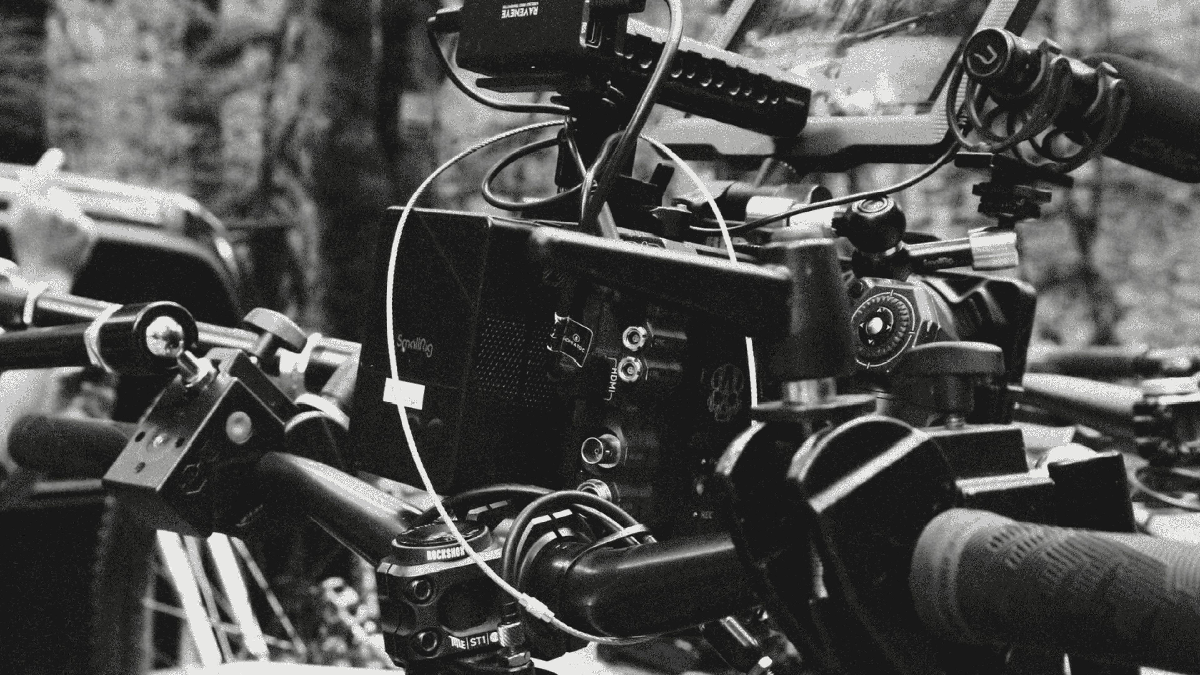 Close-up of a professional video camera rig mounted on handlebars with cables and control knobs visible.