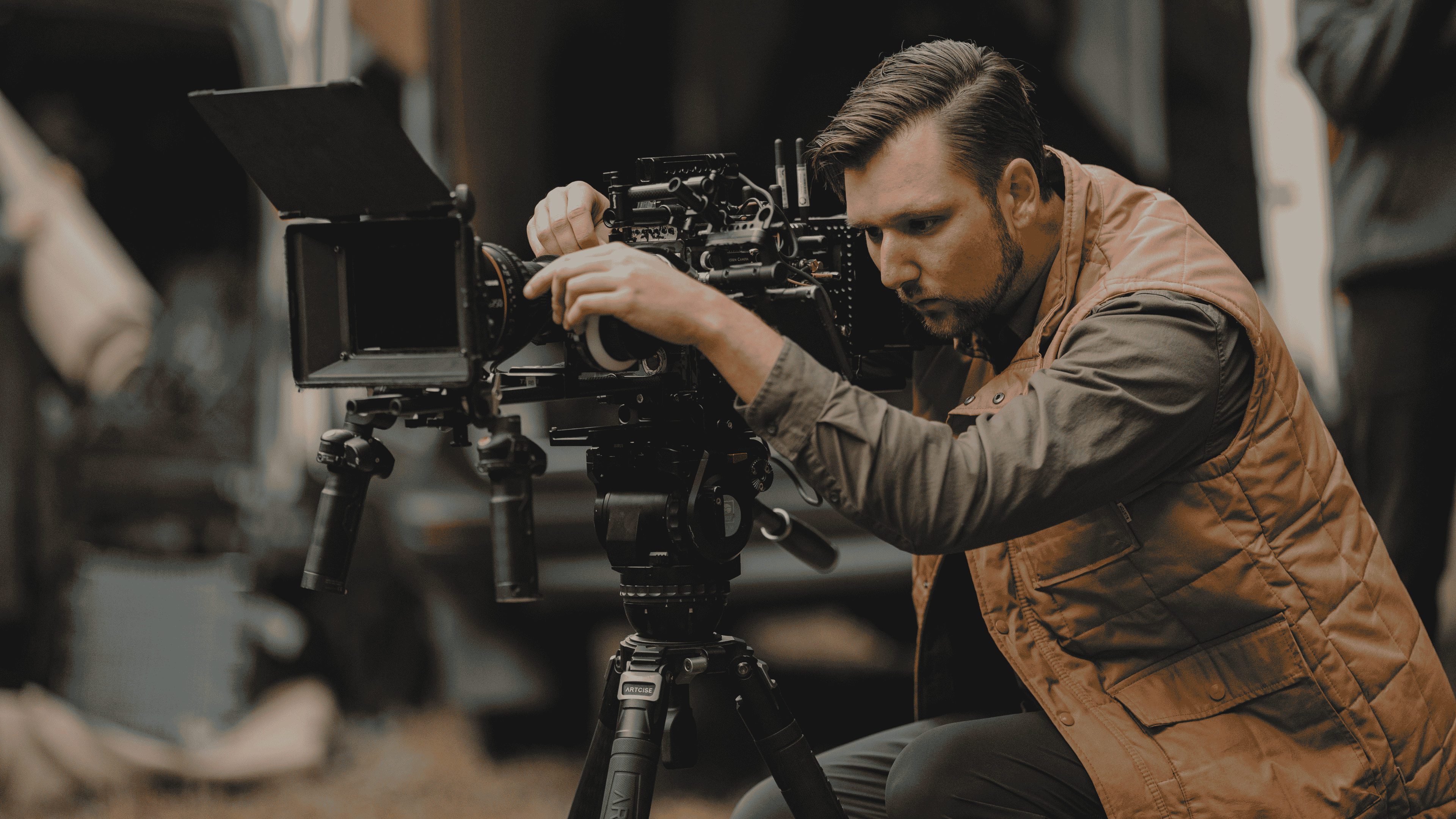 Man adjusting a professional video camera mounted on a tripod.