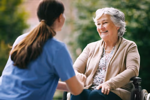 Health aide sitting with elderly woman in a wheelchair