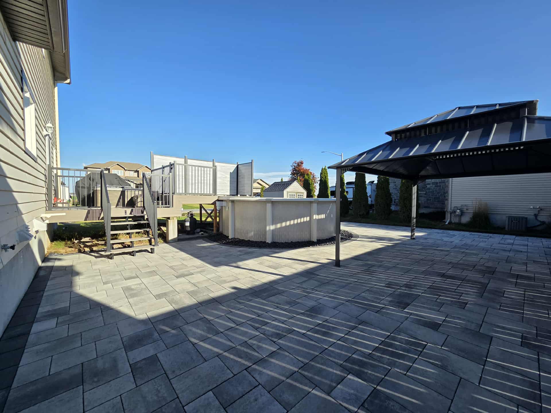 Backyard Stone Patio with above ground pool and gazebo