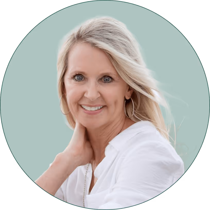 Smiling middle-aged woman with blonde hair wearing a white shirt and hoop earrings against a light green backdrop.
