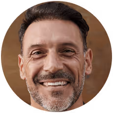 Smiling middle-aged man with short dark hair and trimmed beard against a brown background.