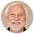 Smiling elderly man with white hair and beard wearing a patterned shirt in a circular frame.