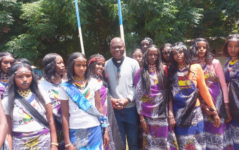 Rev. Fr. Chia Tersugh Emmanuel mit Schülerinnen der Dhadim Catholic School in Äthiopien. Dank der Unterstützung von WMF Barmherzigkeit e.V. erhalten Kinder neue Bildungs- und Entwicklungschancen.