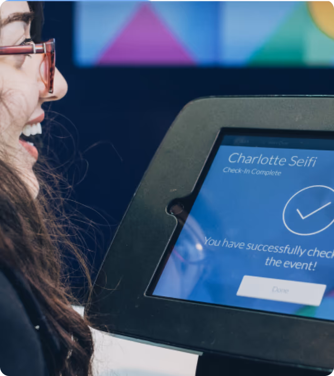 Smiling attendee checking in to an event using a digital tablet kiosk displaying confirmation screen