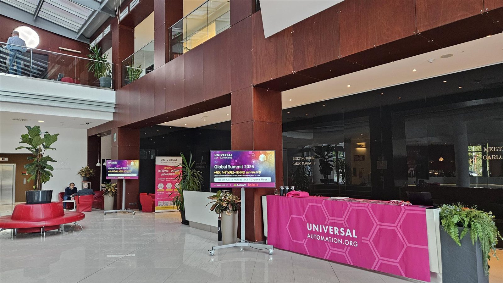 Universal Automation registration desk and screens at the UAO Global Summit 2026, sponsored by Aimirim and Barbara.