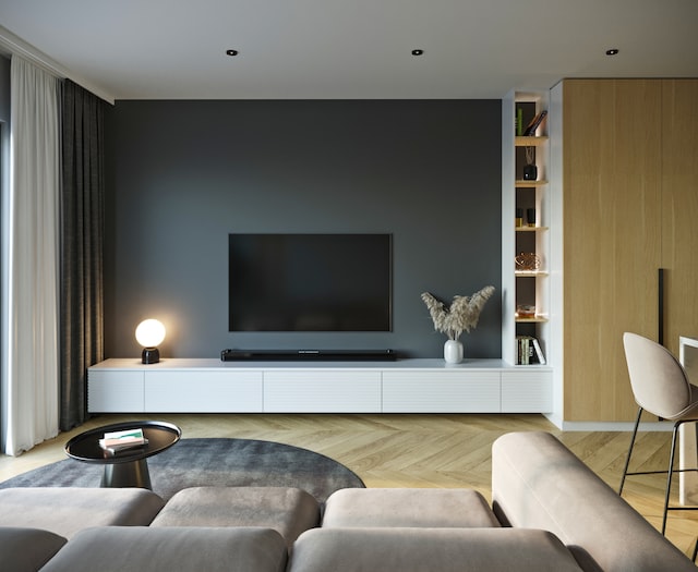 Salon avec télévision fixée sur un mur gris