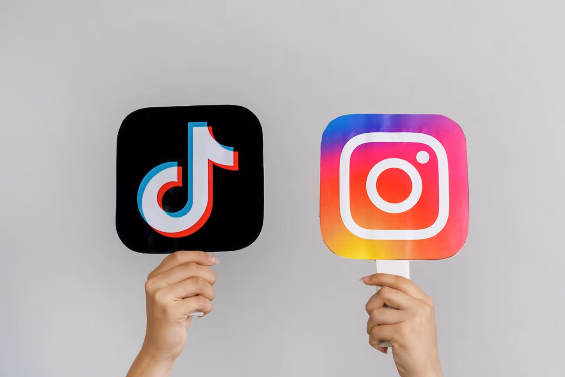 Two hands holding sticks raise the symbols of Instagram and TikTok into the air.